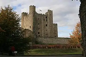 A tall rectangular stone tower with a lower stone wall in front