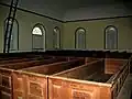 Straight-backed, carved, pews and crude ladder to loft