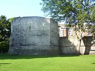 Ancient stone wall and roofless tower with narrow windows.