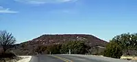 Round Mountain, a butte located 6 mi (9.7 km) to the northwest of Comanche, Texas, where Robert T. Hill first observed Lower Cretaceous fossils and strata. (31°55′30″N 98°42′07″W﻿ / ﻿31.925°N 98.702°W﻿ / 31.925; -98.702) (30 December 2008)