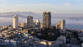 A hill in San Francisco with several tall residential buildings on it. One has a visible FM antenna.