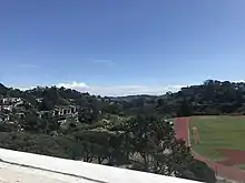 Landscape of a track and field to the right and houses to the left.