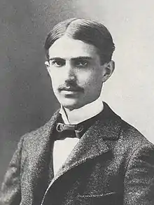 A photograph Stephen Crane in a suit, with parted hair and a mustache