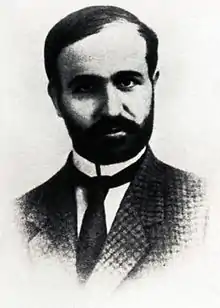 Black and white image of Skliros wearing a jacket and tie