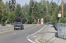 A five-lane road with a single truck, a bicycle lane, and a bus stop sign placed on its sidewalk