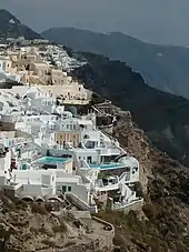 Enclave of structures built into the side of a steep cliff. Swimming pools are visible.