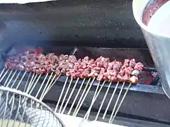 Raw sate kambing (lamb satay) being grilled