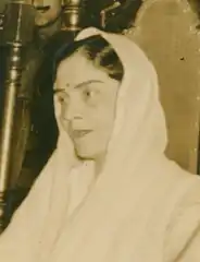 A South Asian woman dressed in white silk, with her head covered.