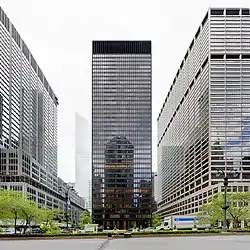 A tall glass tower, as viewed from across Park Avenue. There are two other buildings to the left and right.