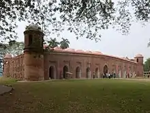 Exterior of a low mosque with many domes and entrances