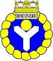 a shakefork—Azure, a shakefork argent supporting in the middle chief a bezant, within an annulet enwreathed, ensigned of a naval crown or, the sails argent, beneath which on a panel argent edged or is the name "Discovery" in letters sable—HM Canadian Ship Discovery