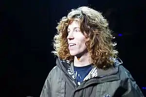 Man with curly brown hair that reaches his shoulders