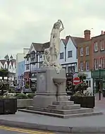 Statue on a plinth of a woman in classical dress carrying a jug on her shoulder and holding a child's hand. Steps up to the base of the plinth lead to a drinking fountain.