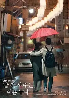 A man puts his arm around a woman as they walk in the rain sharing a red umbrella.