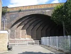 A wide brick arch spanning a narrow road at an oblique angle