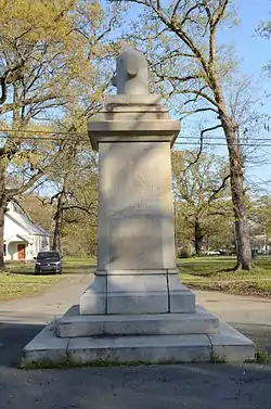 Rectangular stone monument with inscriptions on sides and decorative element atop