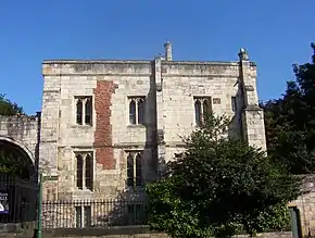 Three storey, flat roofed ancient stone building; graceful pointed arch windows have paned glass.