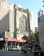 The church shown previously with the sidewalk covered and screens and scaffolding along either side.