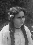 Black and white photo of a bust of a woman with long hair styled in two braids.