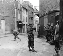 Black and white photograph of men wearing military uniforms in a town