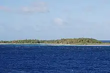 Vegetated green island rising from above the deep blue sea