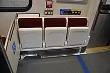 Automatic folding seats in wheelchair accessible position; depending on the individual train, some of these seats use blue velour instead to mark accessibility.