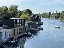 Tagg's Island houseboats, with the Astoria houseboat moored on the northern bank of the River Thames, and St Mary's Church, Hampton in the distance.