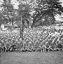 Outdoor photo of a large group of seated men in uniform