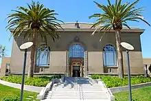 Exterior of the Richmond Branch Library. Entrance stairway is flanked by two large palm trees.