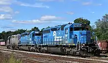 Three blue and gray locomotives in a small rail yard.