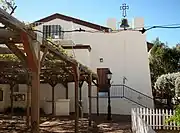 1947 church rear, with 1883 bell and view of a portion of rose arbor to the left