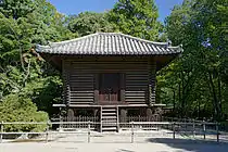 Small and dark wooden building with raised floor on poles.