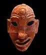 A Punic mask of a face featuring the symbol of Baal Hammon