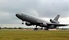 Large gray jet aircraft with three engines (two under the wings and one under the vertical stabilizer). The aircraft had just lifted off from runway, with landing gear fully extended.