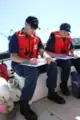 Two Coast Guard auxiliarists review performance qualification workbooks in Portland, Oregon in 2013.