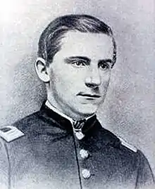 Head and shoulders of a young white man wearing a military jacket with rectangular patches atop each shoulder.