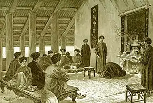 People in the Nguyễn dynasty with khăn vấn. The people in the back are sitting on a sập.