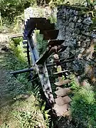 Photograph of an abandoned water wheel near a hiking path.