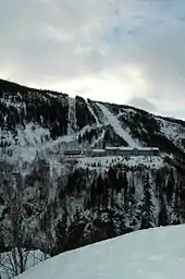 Snow covered winter wooded landscape, with factory on opposite slope of hills