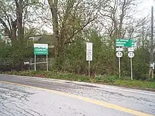 Ground-level view of a road with a series of signs visible on the right side.