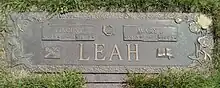 Flat brozne plaque with the family name Leah centred at the bottom, and the names of Vince and Mary above with their birth and death years