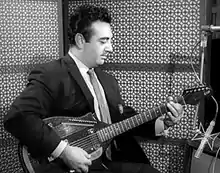 Black-and-white photo of guitarist wearing a suit while playing in the studio