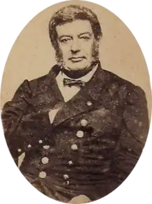 Photographic portrait of a dark-haired man with sideburns, dressed in a double-breasted military tunic with his right hand tucked under the lapel of his jacket