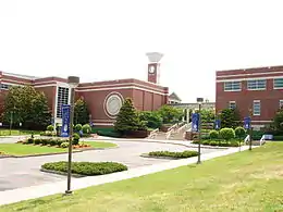 Brick buildings set behind a green lawn with parking lot