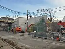 Construction of a retaining wall next to an urban street, with a railroad bridge behind