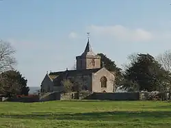 Stone building with square tower topped by a small spires.