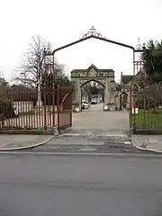 Entrance gates on Norwood Road leading to the original 1837 gates. On left is Commonwealth War Graves Commission Cross of Sacrifice memorial