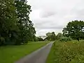 House in distance, what remains of an avenue of tall trees can be made out