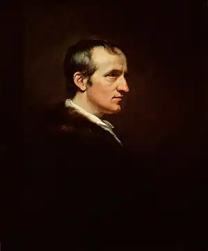 Half-length profile portrait of a man. His dark clothing blends into the background and his white face is in stark contrast.