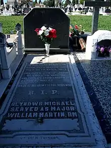 A large black marble memorial slab with flowers